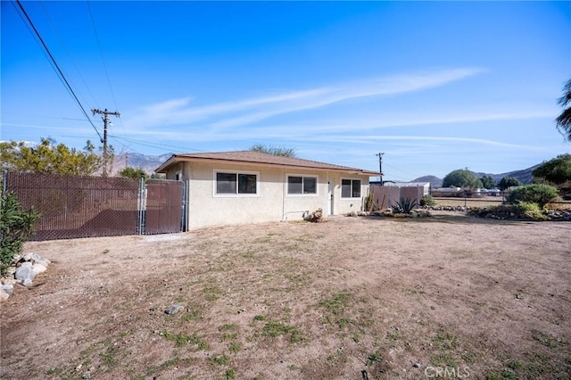 back of property featuring a gate, fence, and stucco siding