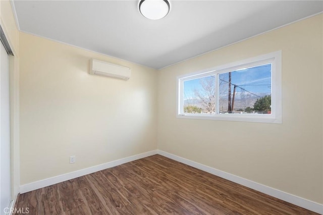 spare room with baseboards, dark wood-type flooring, and an AC wall unit