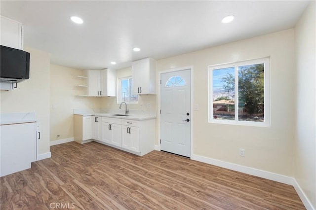 kitchen with white cabinetry, open shelves, a sink, and wood finished floors