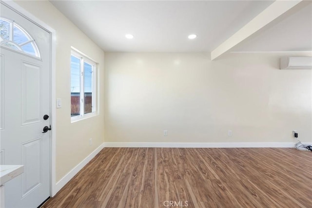 foyer entrance with recessed lighting, an AC wall unit, baseboards, and wood finished floors