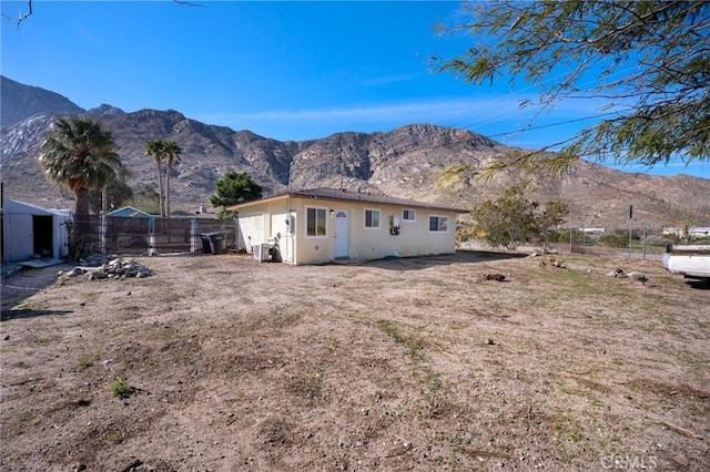 rear view of property with fence, a mountain view, and cooling unit