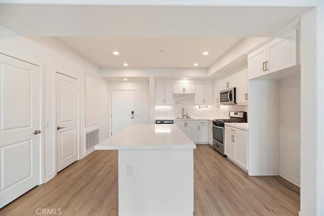 kitchen featuring stainless steel appliances, light wood-type flooring, a sink, and visible vents