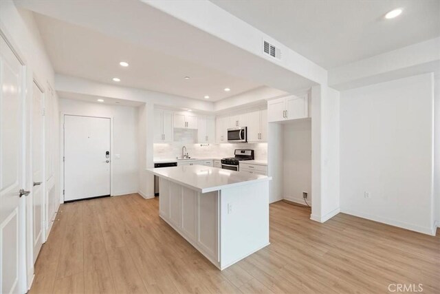 kitchen with visible vents, white cabinets, light countertops, appliances with stainless steel finishes, and light wood finished floors