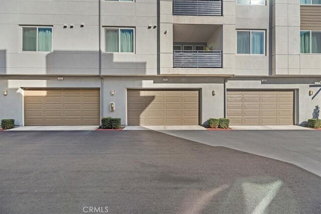 exterior space featuring a garage, driveway, and stucco siding