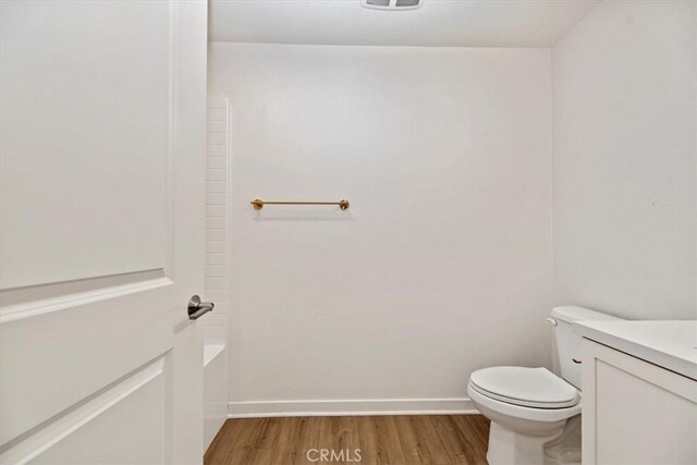 bathroom with vanity, wood finished floors, toilet, and baseboards