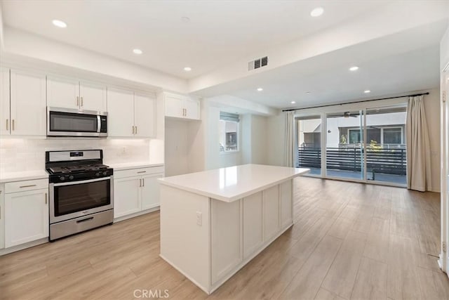 kitchen with stainless steel appliances, visible vents, backsplash, and white cabinetry