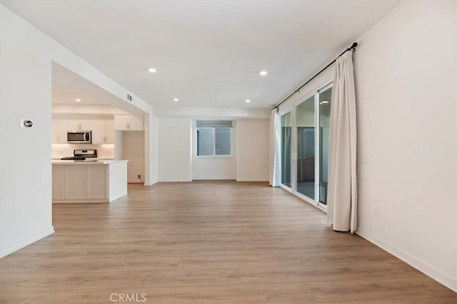 unfurnished living room featuring baseboards, light wood-style flooring, and recessed lighting