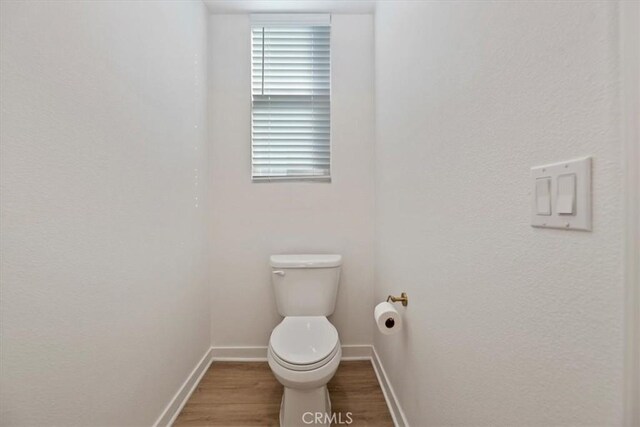 bathroom featuring toilet, baseboards, and wood finished floors