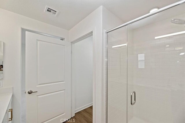 bathroom with a stall shower, visible vents, wood finished floors, and vanity