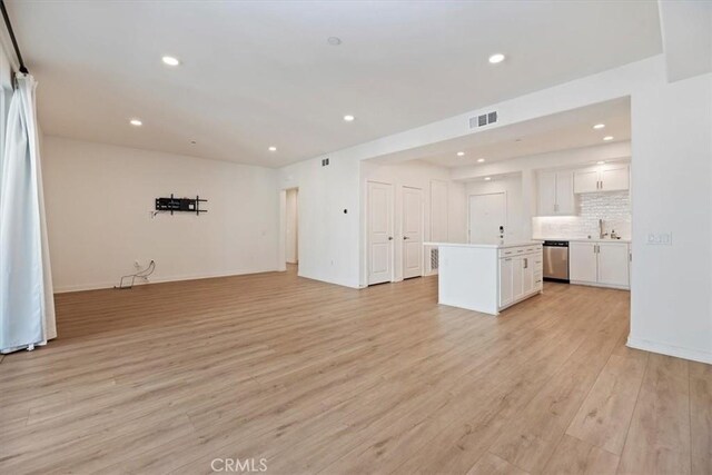 unfurnished living room with recessed lighting, visible vents, light wood-style flooring, a sink, and baseboards