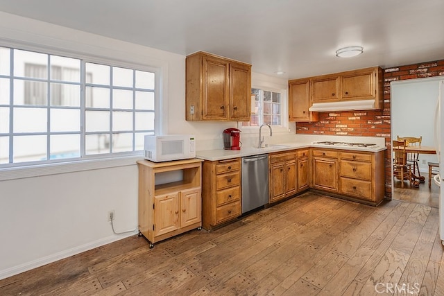 kitchen featuring white appliances, light wood-style floors, light countertops, under cabinet range hood, and a sink