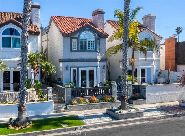 mediterranean / spanish house featuring a tiled roof, stucco siding, and french doors