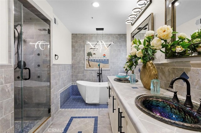 bathroom featuring a stall shower, double vanity, a sink, and tile walls