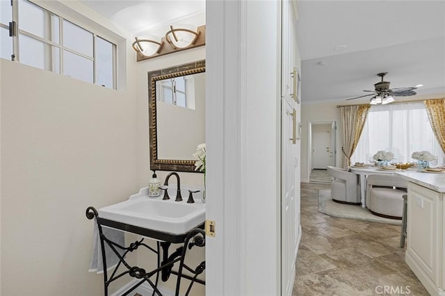 bathroom with ornamental molding, a ceiling fan, and a sink