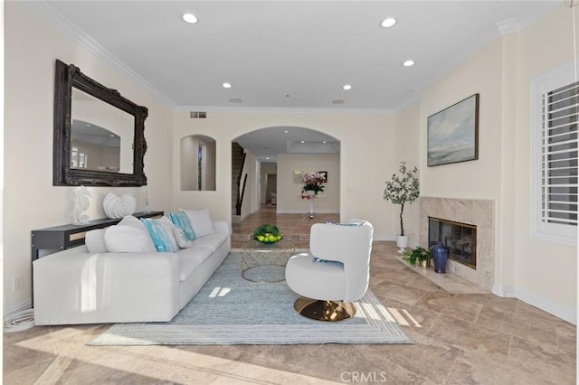 living room with arched walkways, recessed lighting, crown molding, and a premium fireplace