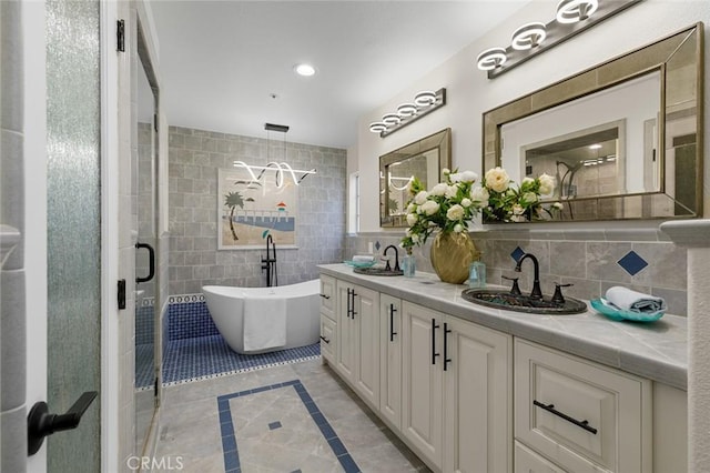 bathroom featuring double vanity, a soaking tub, tile walls, and a sink