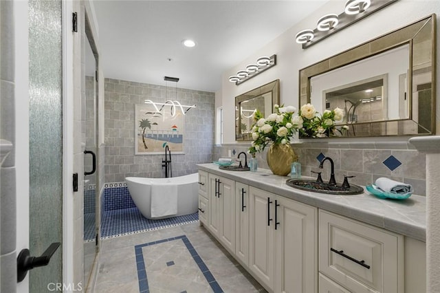 bathroom with a sink, tile walls, a freestanding bath, and double vanity