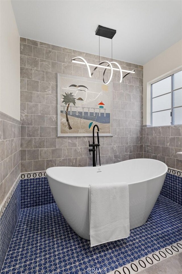 full bath with a tile shower, tile walls, a freestanding tub, and tile patterned flooring