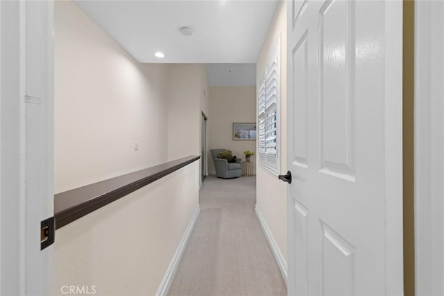 hallway featuring baseboards, recessed lighting, and light carpet