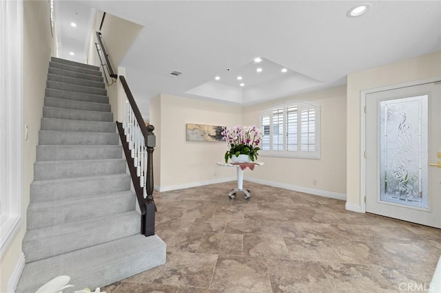 entrance foyer with visible vents, baseboards, a raised ceiling, stairway, and recessed lighting
