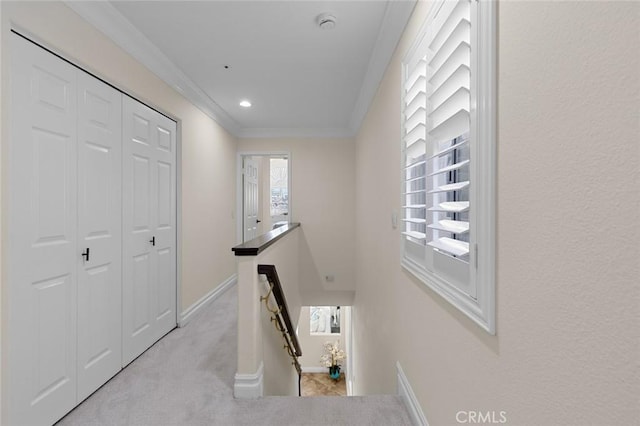 corridor featuring an upstairs landing, light carpet, crown molding, and baseboards