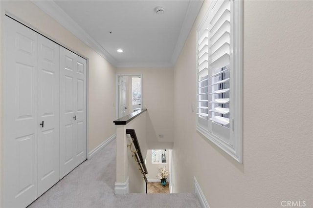 hall featuring an upstairs landing, light colored carpet, baseboards, and ornamental molding