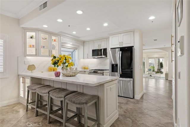 kitchen with a kitchen bar, a peninsula, light stone counters, and stainless steel appliances