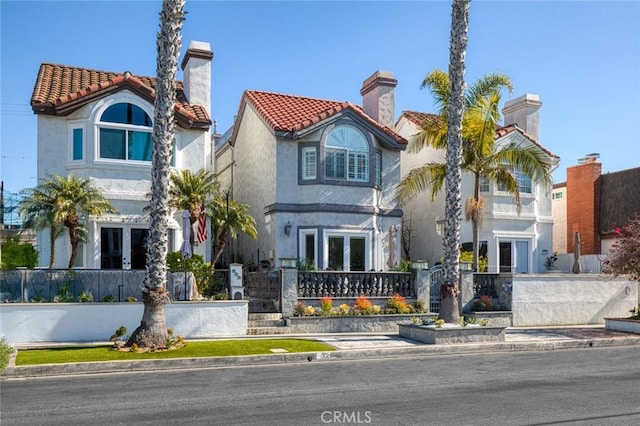 mediterranean / spanish-style house featuring french doors, a fenced front yard, and stucco siding