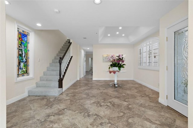 entrance foyer featuring recessed lighting, stairway, baseboards, and a raised ceiling