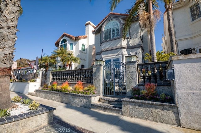 view of front of property featuring a fenced front yard, a tile roof, stucco siding, and a gate