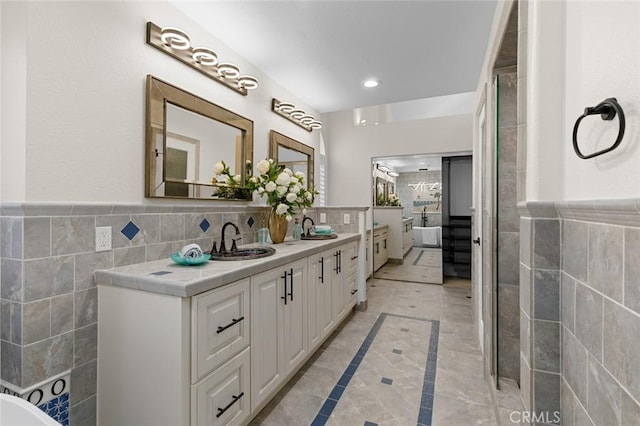 bathroom featuring double vanity, ensuite bathroom, tile walls, and a sink