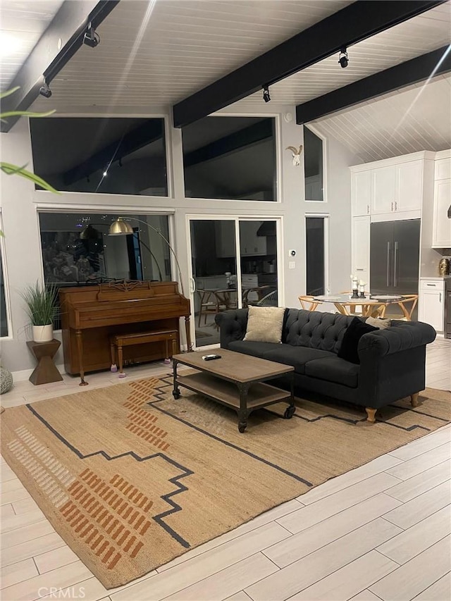 living room with track lighting, beam ceiling, high vaulted ceiling, and light wood finished floors