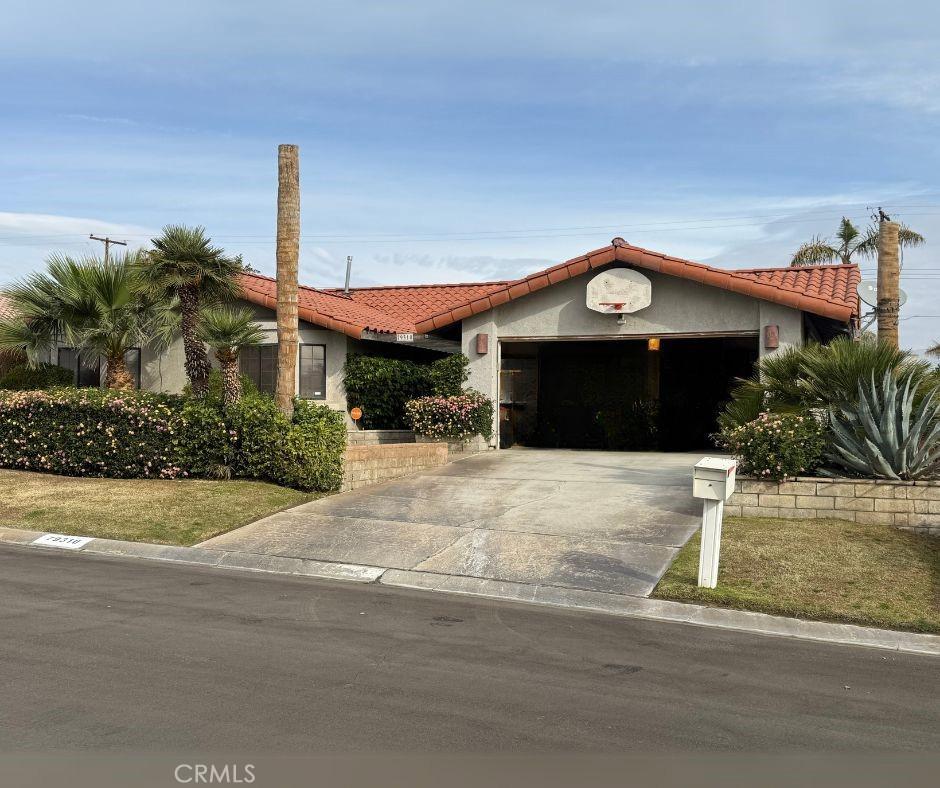 view of front facade with driveway, an attached garage, a tiled roof, and stucco siding