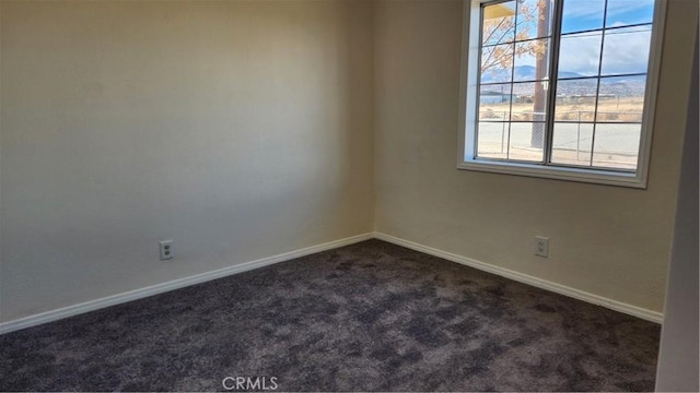 empty room featuring dark carpet and baseboards