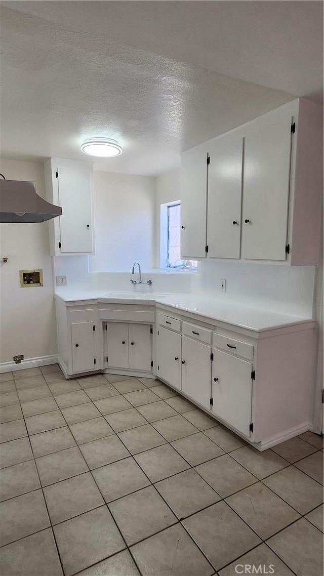 kitchen featuring a textured ceiling, light countertops, a sink, and white cabinetry