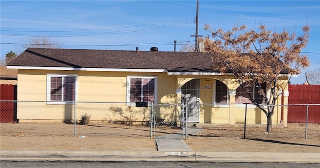 view of front of property with a fenced front yard, roof with shingles, and stucco siding