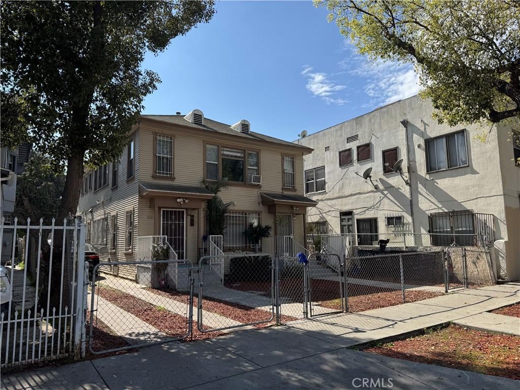 multi unit property featuring a fenced front yard and a gate