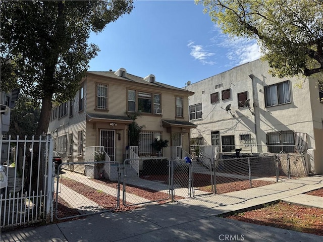 multi unit property featuring a fenced front yard and a gate