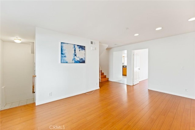 empty room featuring recessed lighting, visible vents, light wood-style flooring, stairway, and baseboards