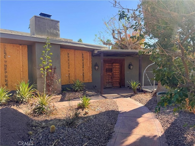 exterior space with a chimney and stucco siding