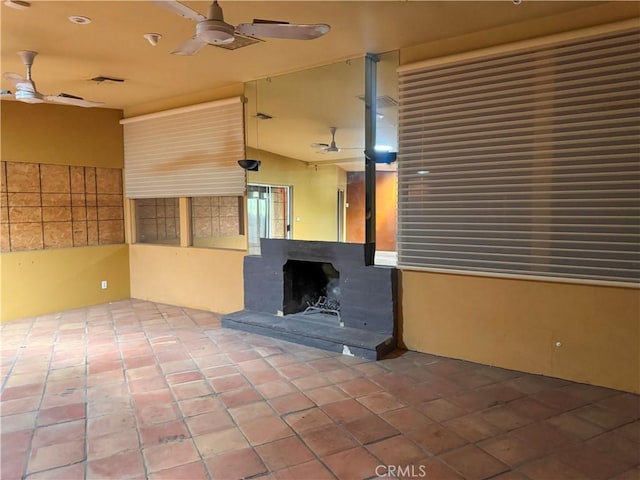 interior space with ceiling fan, visible vents, and a fireplace with raised hearth