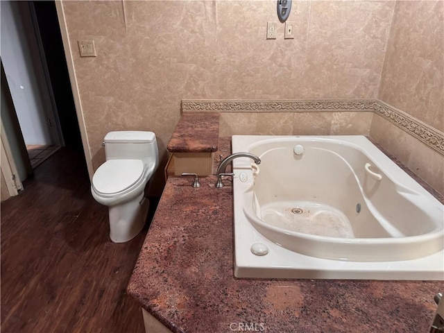 bathroom with a jetted tub, wood finished floors, and toilet