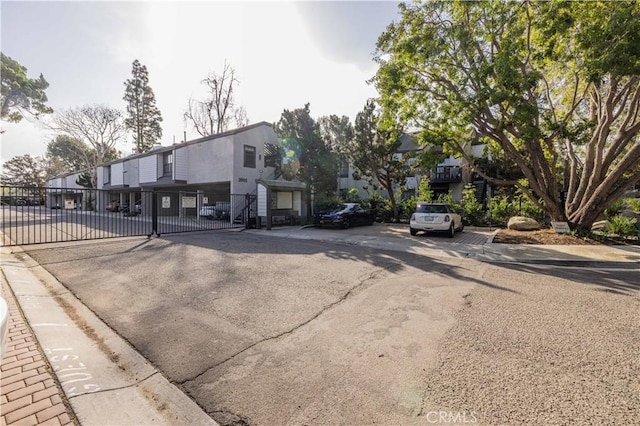 view of road featuring sidewalks, a residential view, a gated entry, and curbs