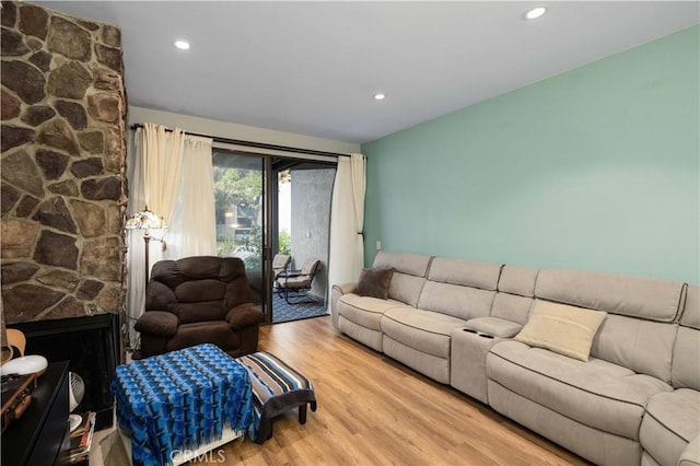 living room featuring recessed lighting, a stone fireplace, and wood finished floors