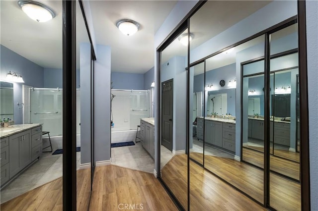 full bath featuring a garden tub, walk in shower, two vanities, and wood finished floors