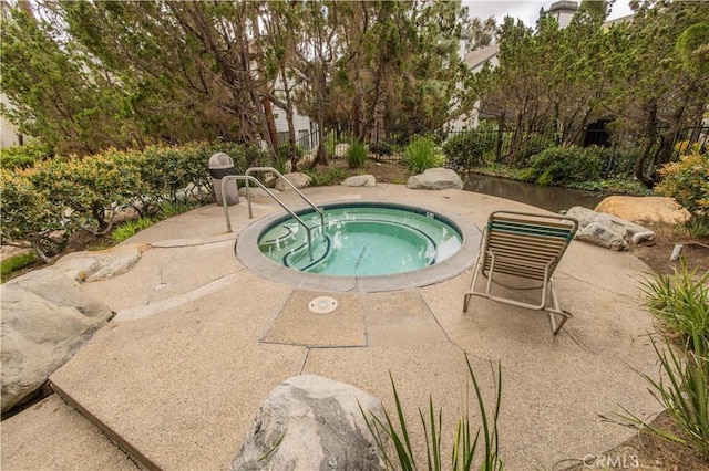 view of swimming pool featuring a community hot tub, fence, and a patio