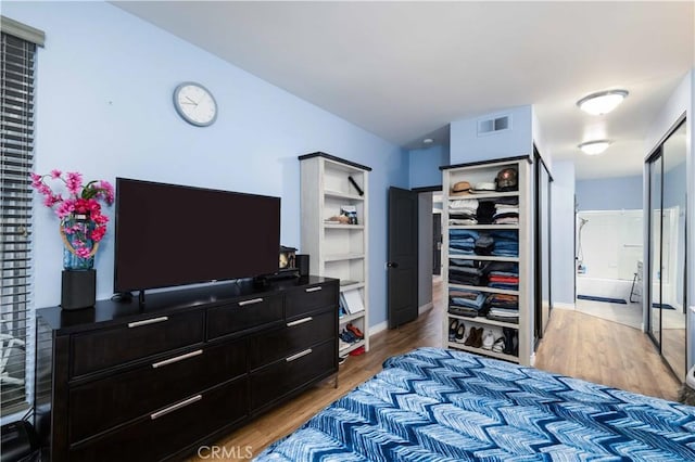 bedroom with light wood-type flooring, visible vents, and baseboards