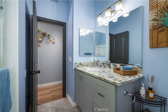 full bath with tile patterned floors, baseboards, and vanity