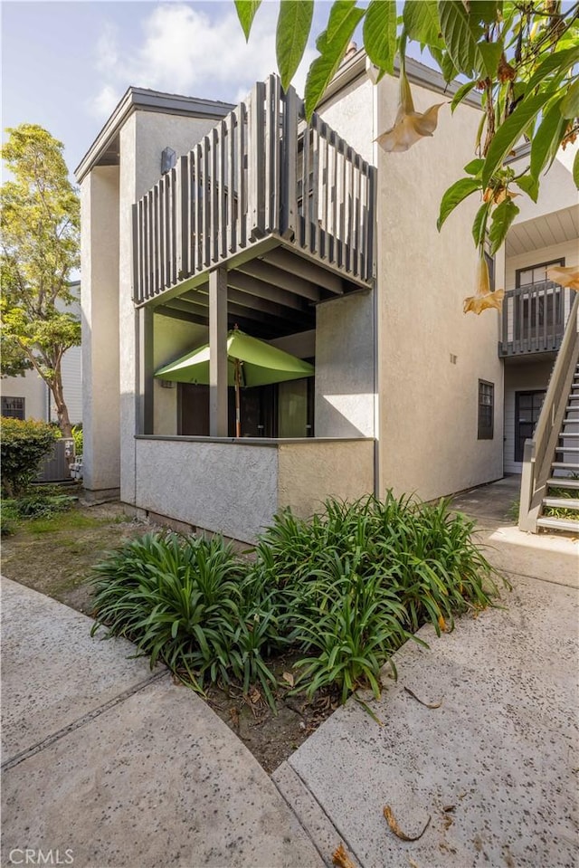 view of side of home with stairs and stucco siding