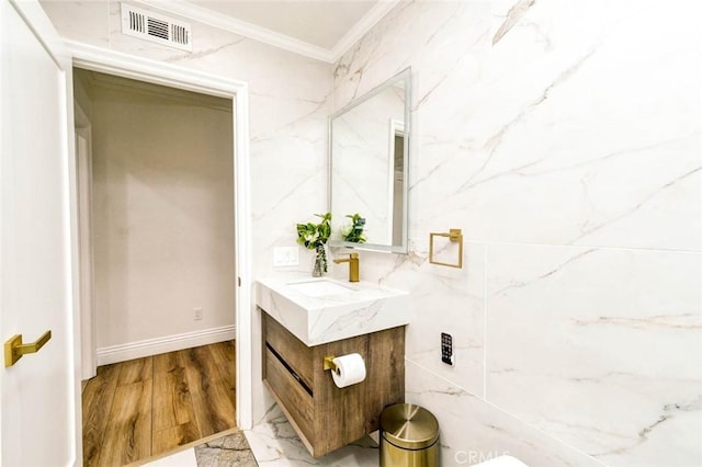bathroom featuring ornamental molding, vanity, baseboards, and wood finished floors